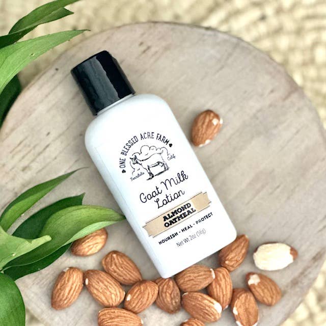 2 oz Almond Oatmeal Goat Milk Lotion by One Blessed Acre Farm with almonds and leaves on a wooden surface
