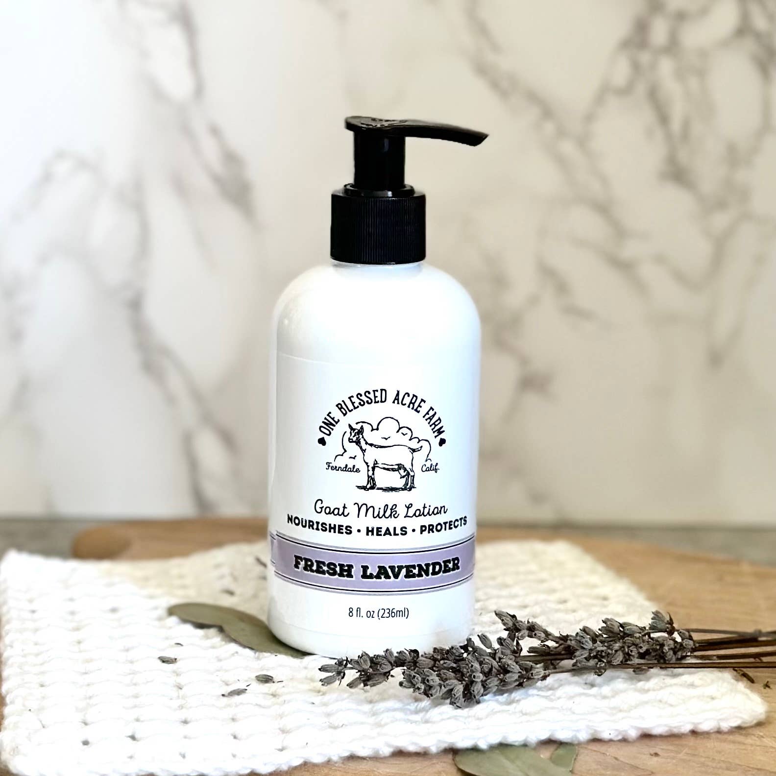8oz Fresh Lavender Goat Milk Lotion by One Blessed Acre Farm on a textured surface with lavender flowers