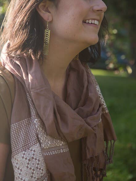 A woman wearing the Mauve Patterned Scarf by Fair Anita paired with gold earrings.