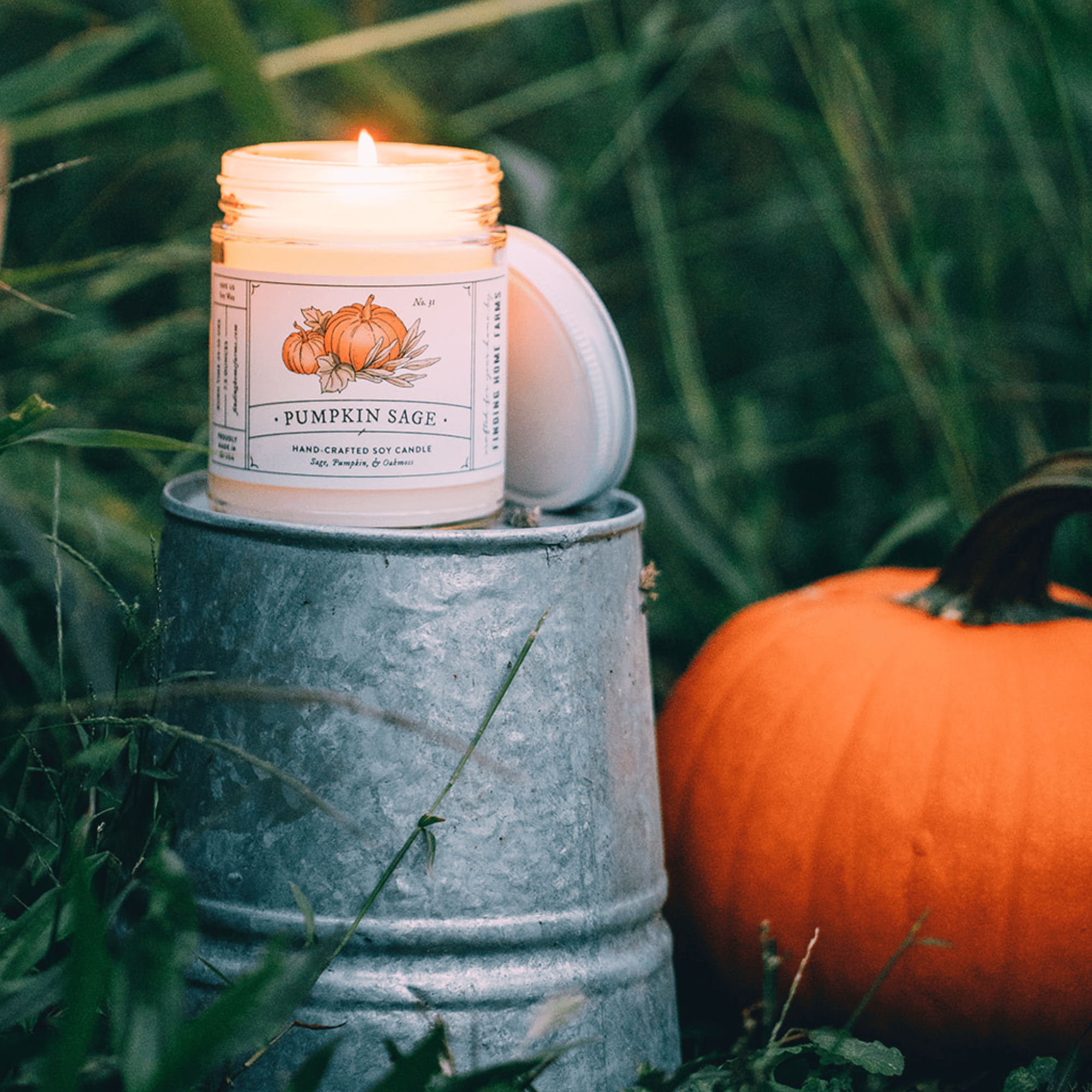 Pumpkin Sage Soy Candle by Finding Home Farms on a metal bucket with a pumpkin in the background