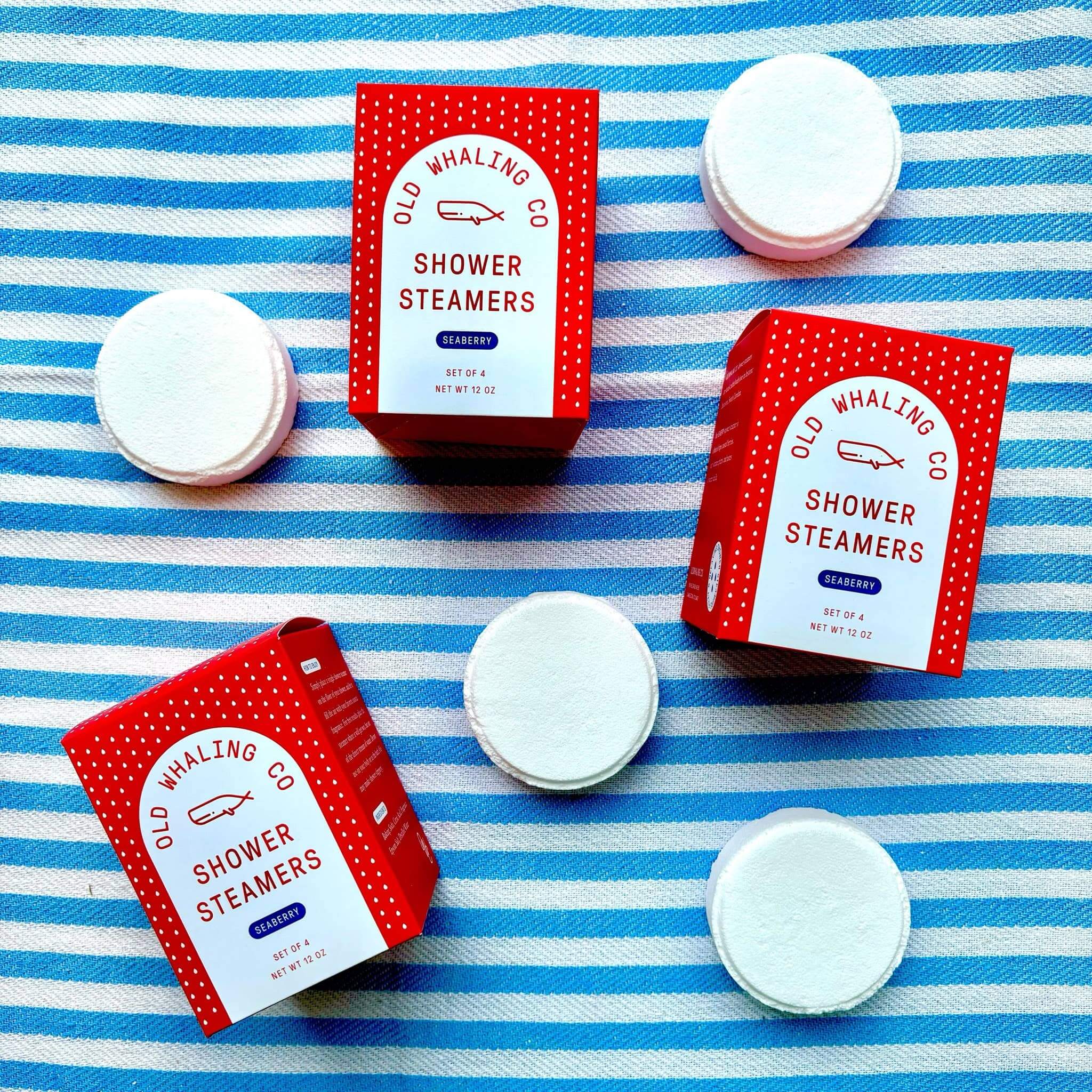 Up-close version of Seaberry shower steamers by Old Whaling Co laid out on a blue white stripe towel