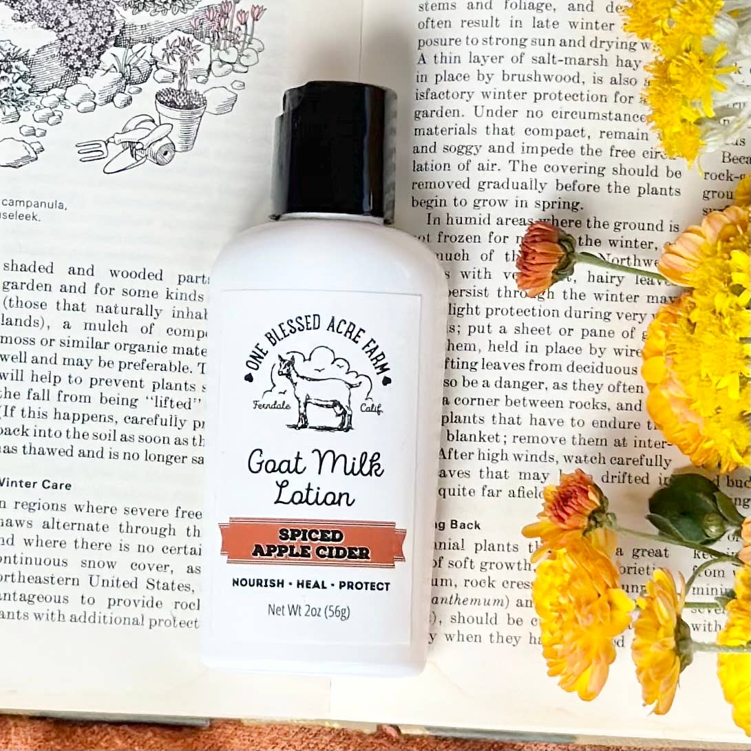 2 oz Spiced Apple Cider Goat Milk Lotion by One Blessed Acre Farm on a book with floral decorations