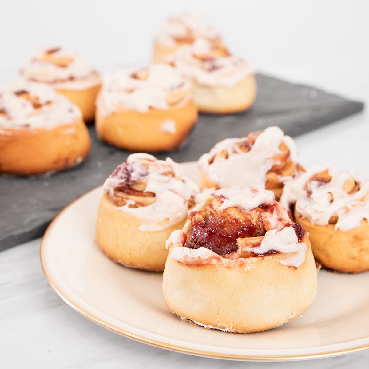 Cinnamon rolls with icing and Cranberry Medley Jam on a plate and tray