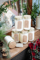 Jars of Fraser Fir Soy Candle by Eco Candle Company  on a wooden surface with plants in the background