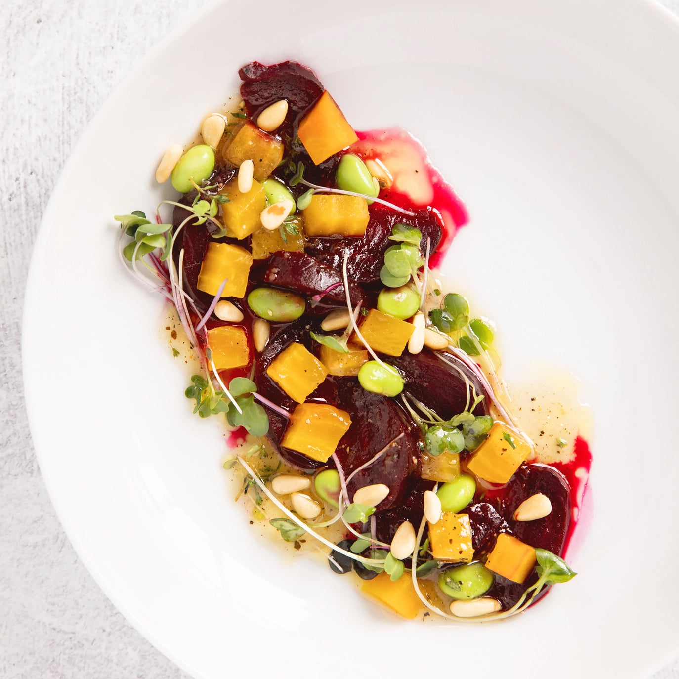 Colorful salad with beets, mango, and edamame on a white plate with dressing made with Lemon Champagne Jam by Blake Hill Preserves