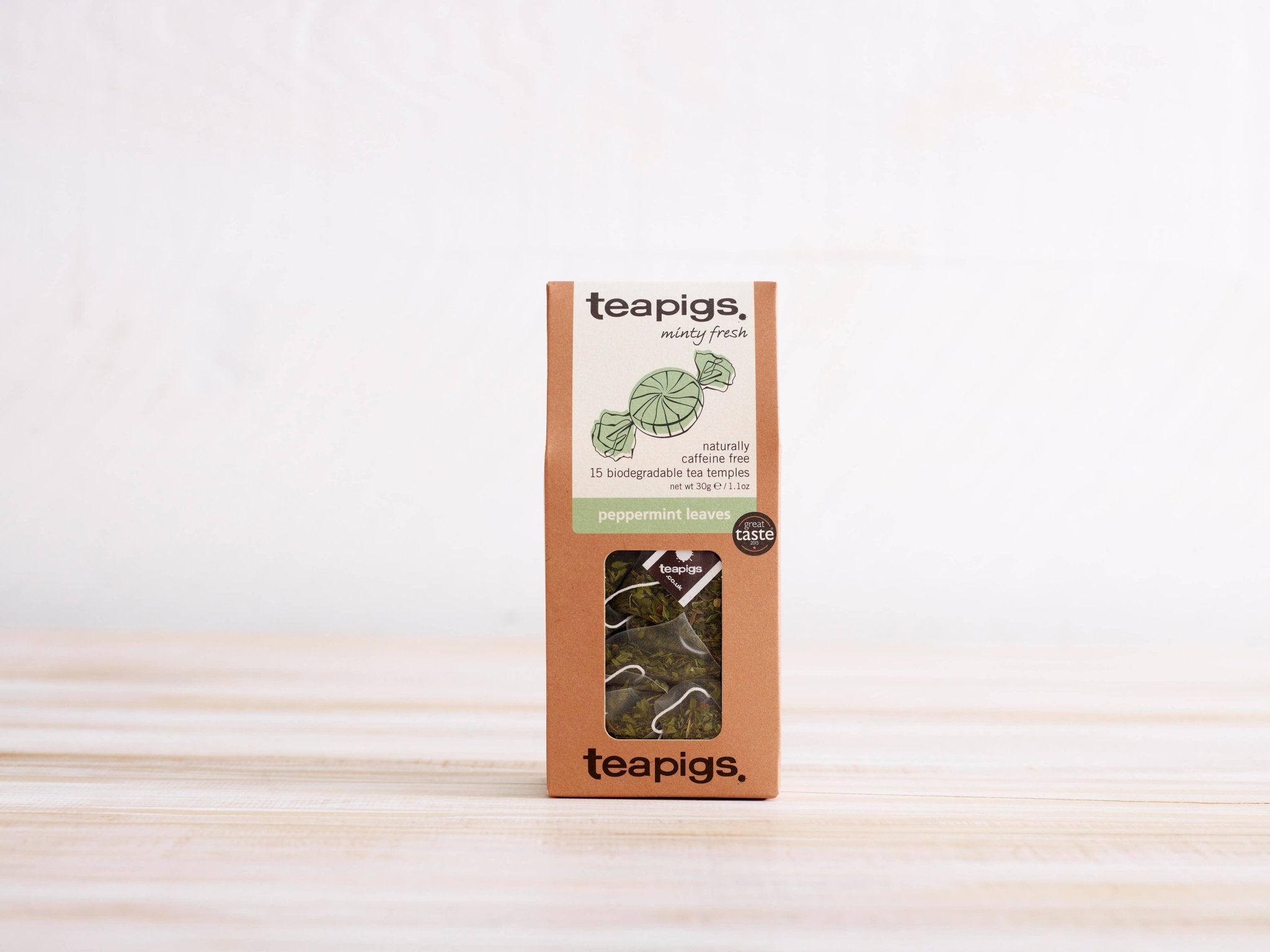 Teapigs peppermint tea packaging on a wooden surface with a white background