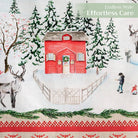 A close-up of the Rural Christmas Table Runner by Maison d'Hermine, featuring an illustration of a red house with a wreath, surrounded by trees and a reindeer.