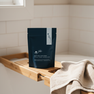 Sleep Well Bath Soak Lavender scented bath soak pouch displayed on bathtub ledge in neutral bathroom