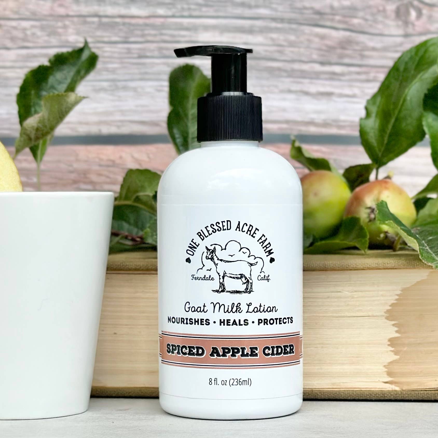 8 oz bottle of spiced apple cider goat milk lotion by One Blessed Acre Farm with a rustic background