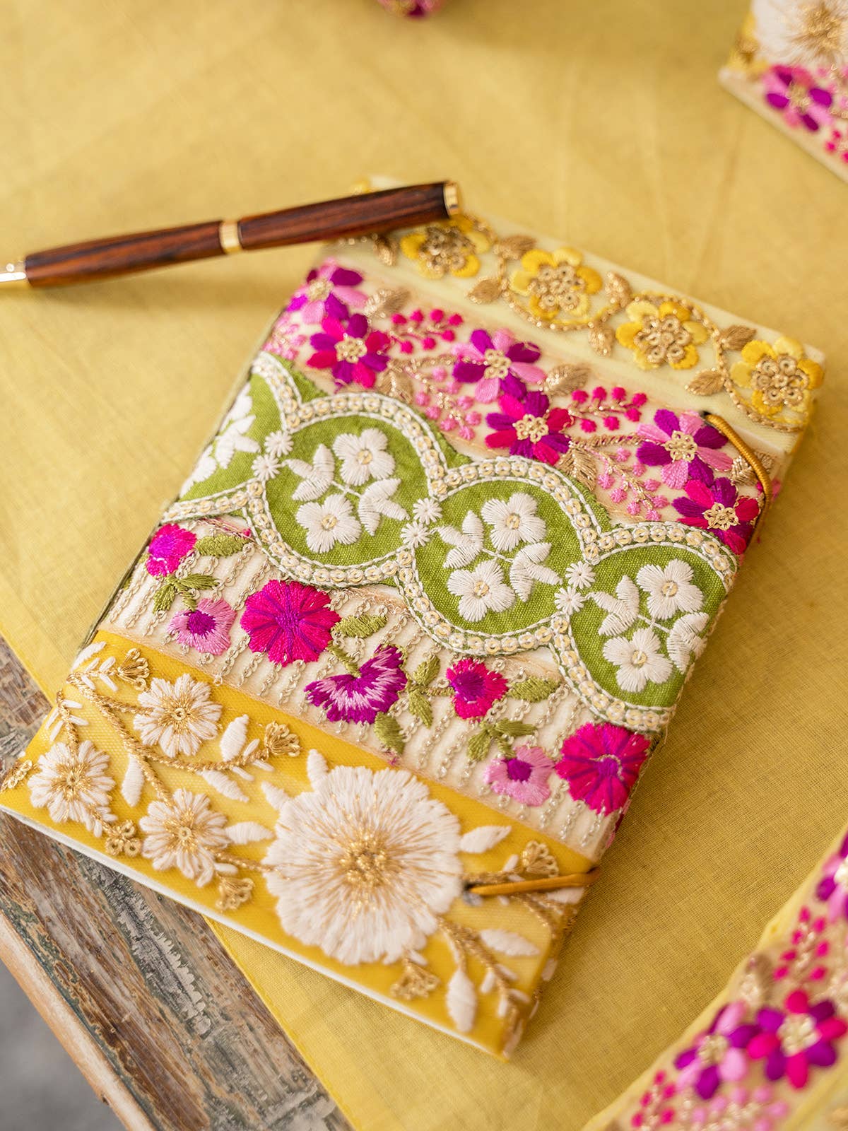 Bel Canto Saffron Magenta Notebook by April Cornell. Notebook is covered in Lace Ribbon trims are a mix of polyester, rayon, zari & sequin.