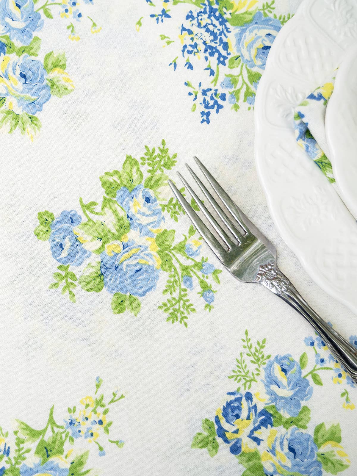 Upclose of Estella tablecloth print by April Cornell. White background with blue and yellow flowers.